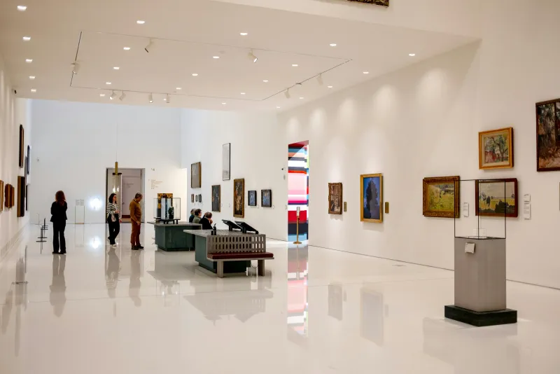 Modern museum wing with glass facade and visitors approaching the entrance.