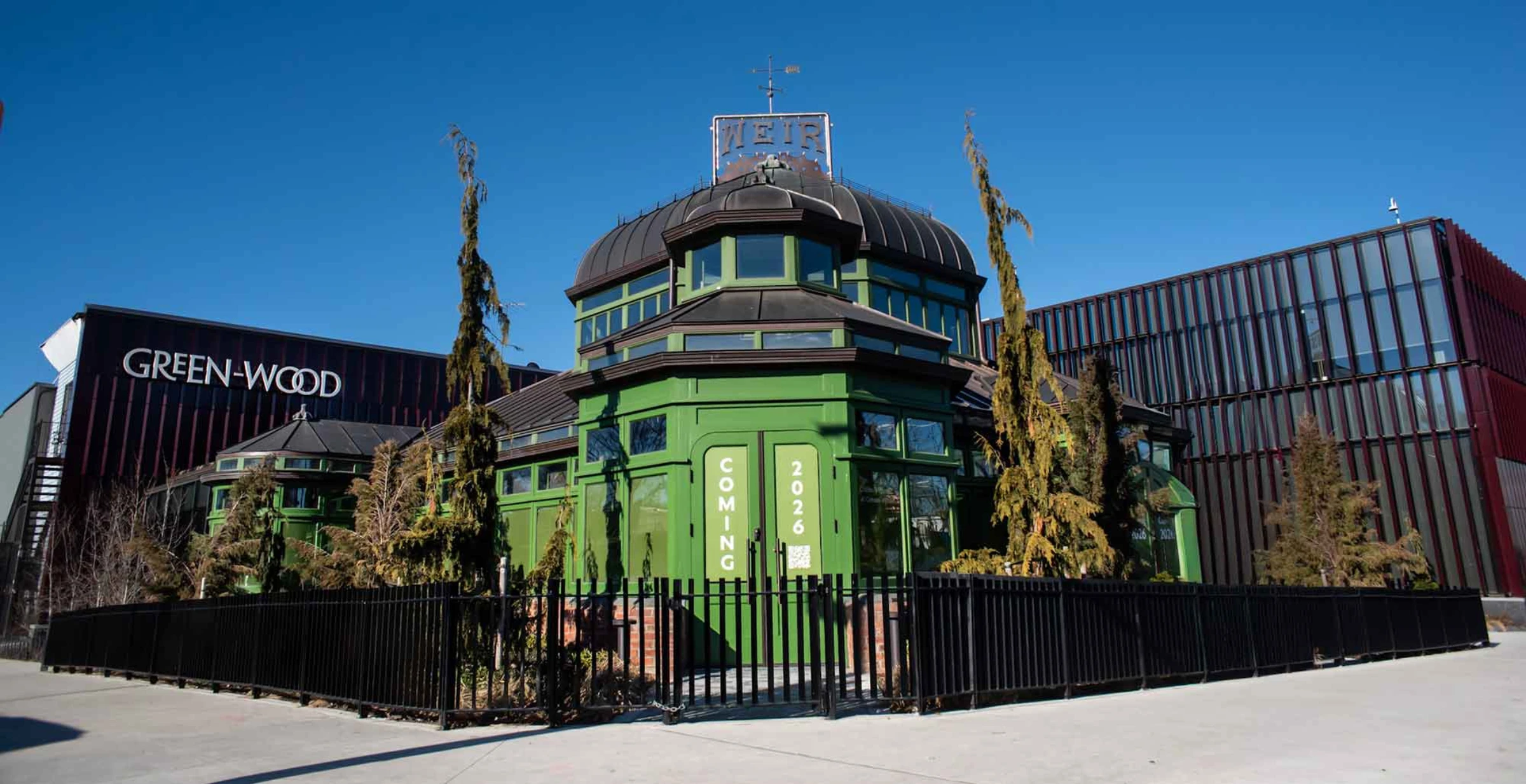 Exterior view of Green-Wood Cemetery's new Green-House welcome center in Brooklyn, with the restored Victorian glasshouse integrated into a contemporary building.