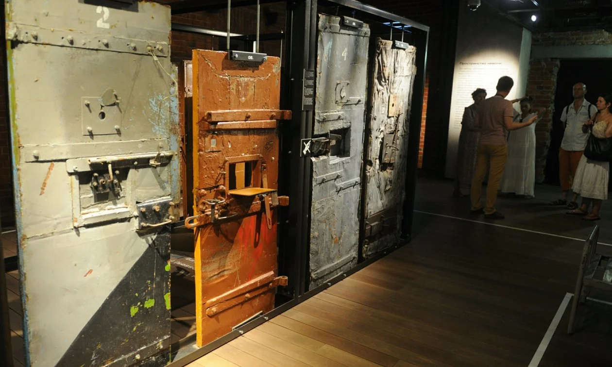 Original gulag prison cell doors displayed at the GULAG History Museum in Moscow, with visitors examining the exhibition