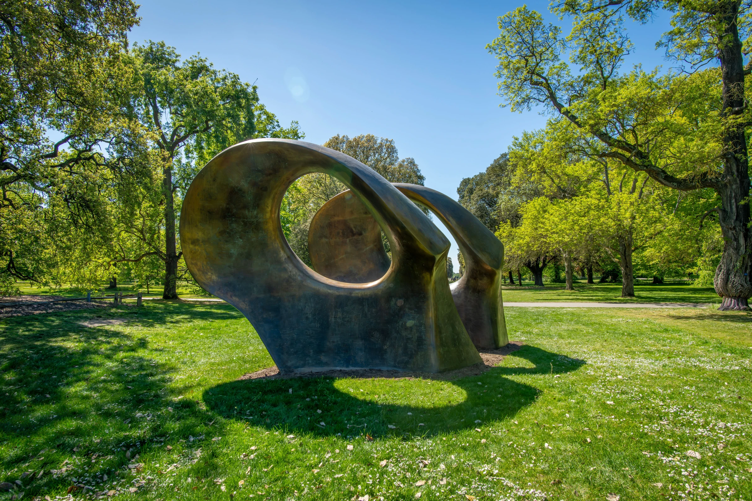 Henry Moore bronze sculpture installed outdoors at Kew Gardens with trees and foliage visible behind it