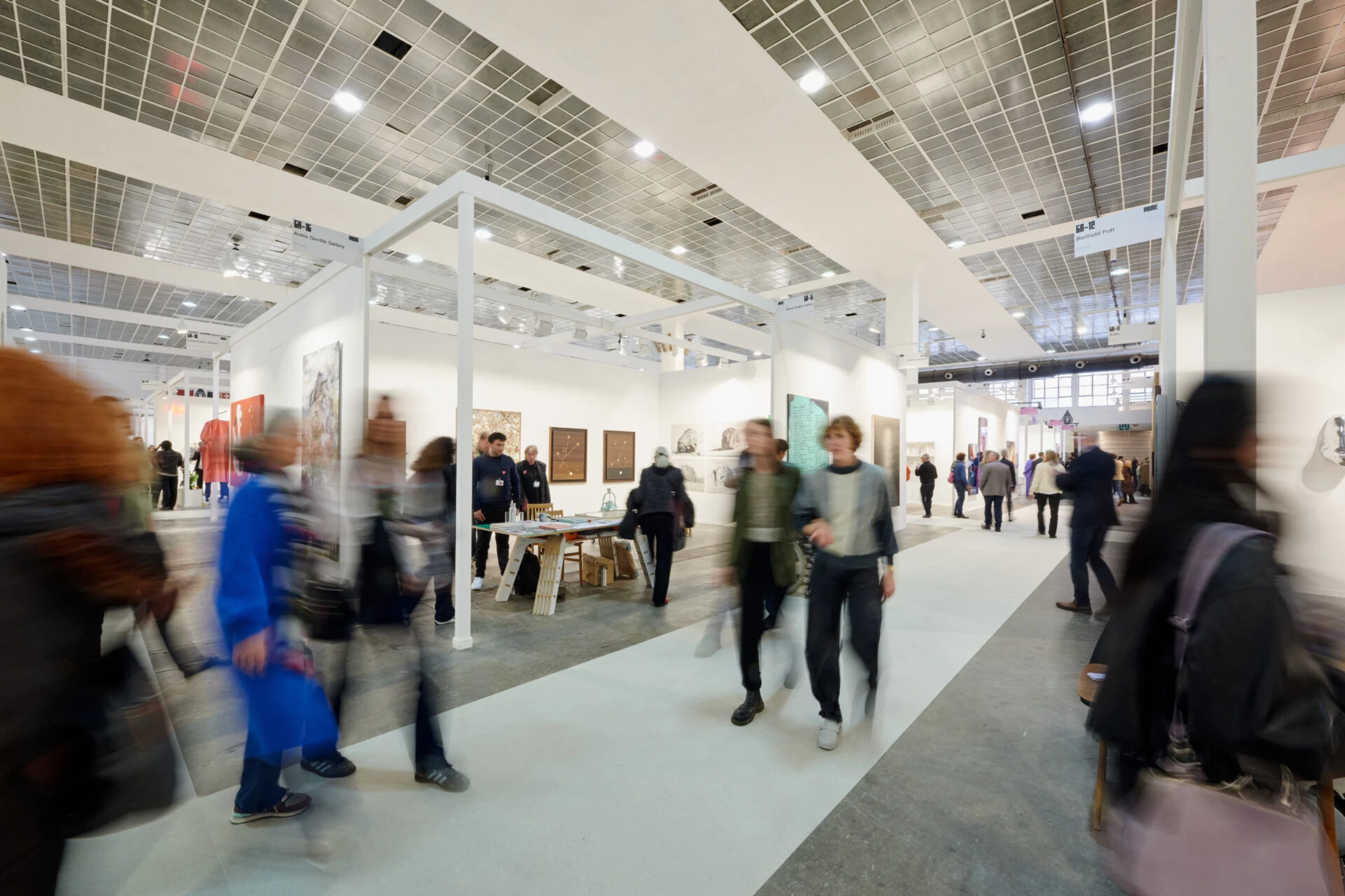 Visitors moving through a contemporary art fair with multiple gallery booths.