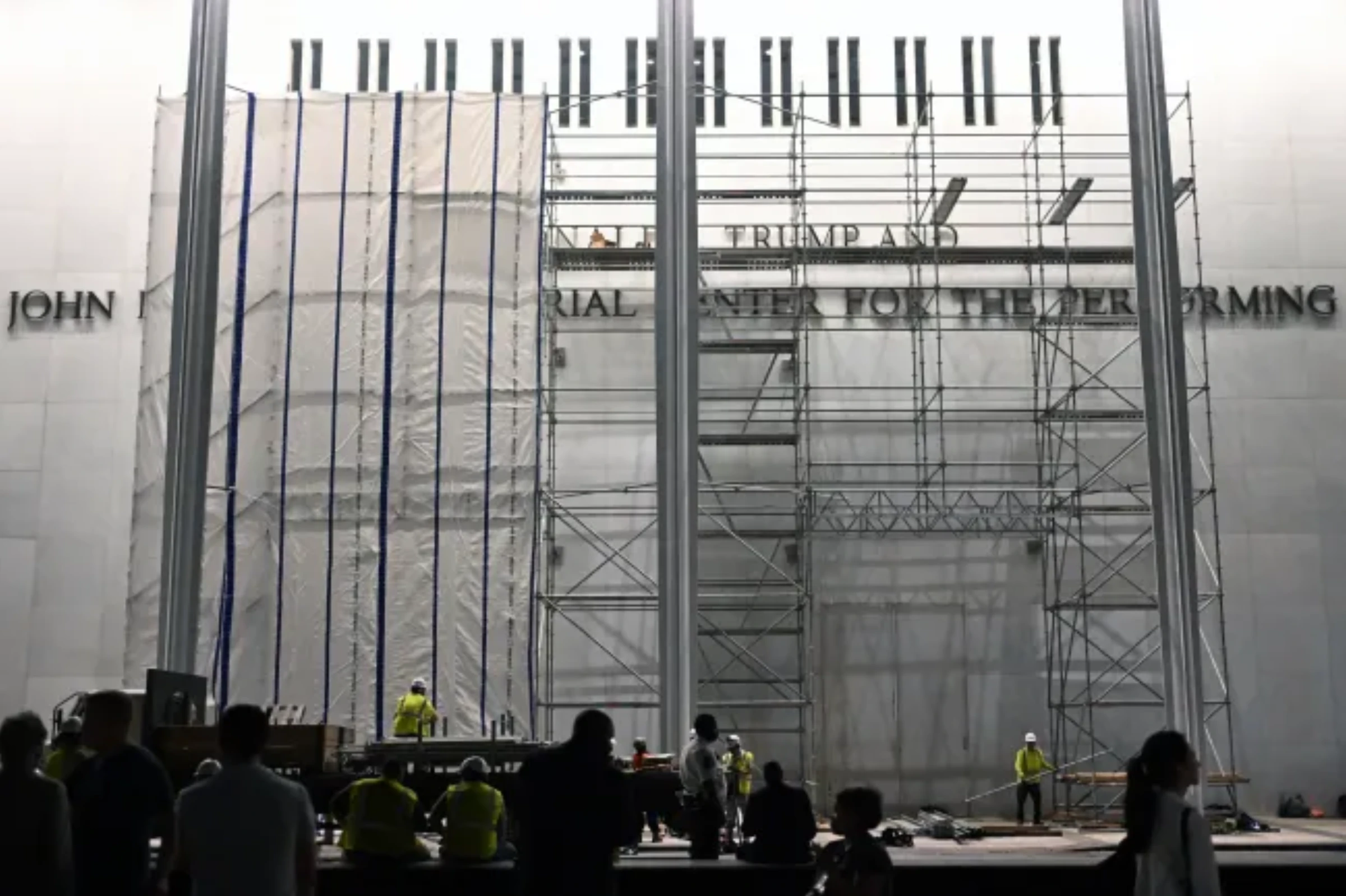 Workers hanging a large tarp over the facade of the Kennedy Center in Washington D.C.