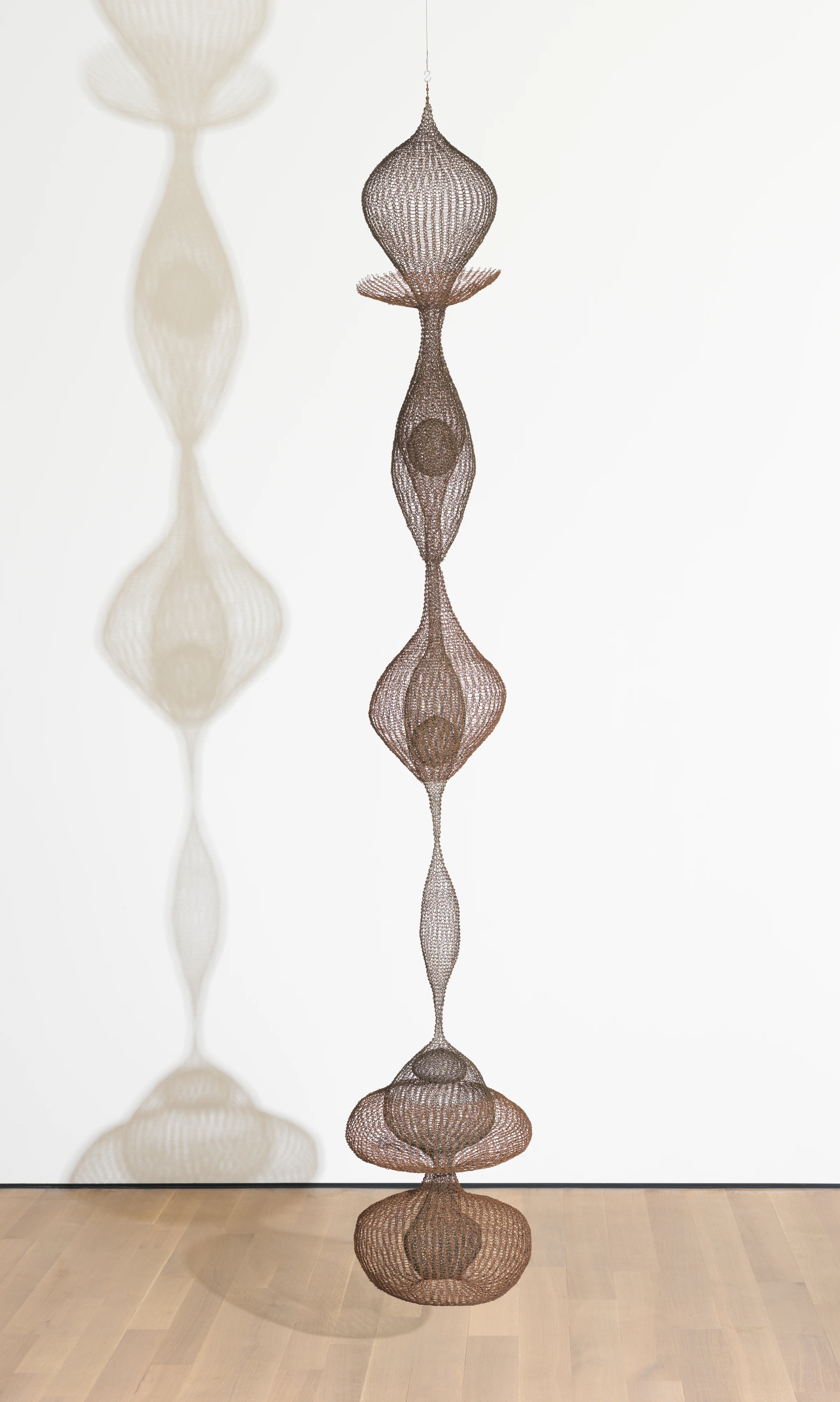 A suspended wire sculpture by Ruth Asawa installed in a museum gallery.