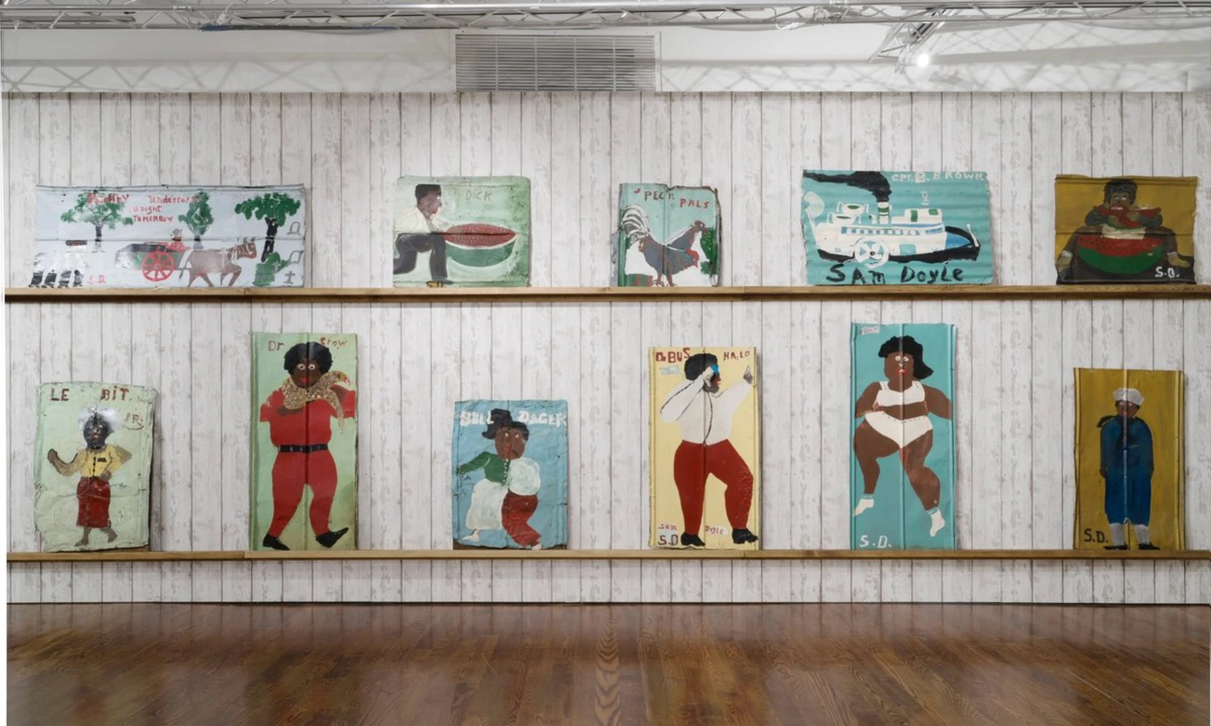 Colorful portraits by self-taught artist Sam Doyle shown in a fair booth setting.