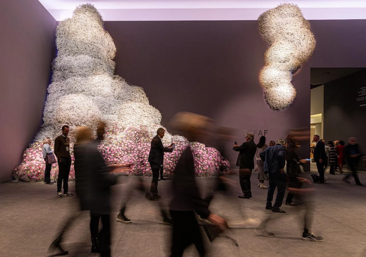 Visitors at TEFAF Maastricht beside a large-scale floral installation in the fair entrance hall.